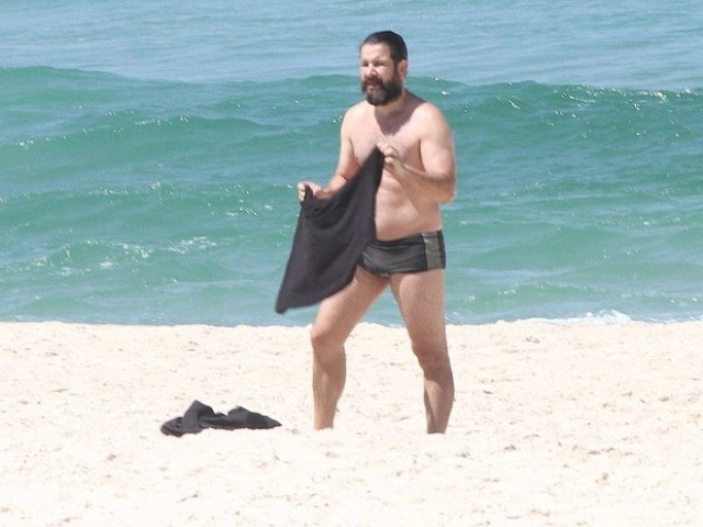 Barbudo, Murilo Benício mostra barriguinha avantajada em praia