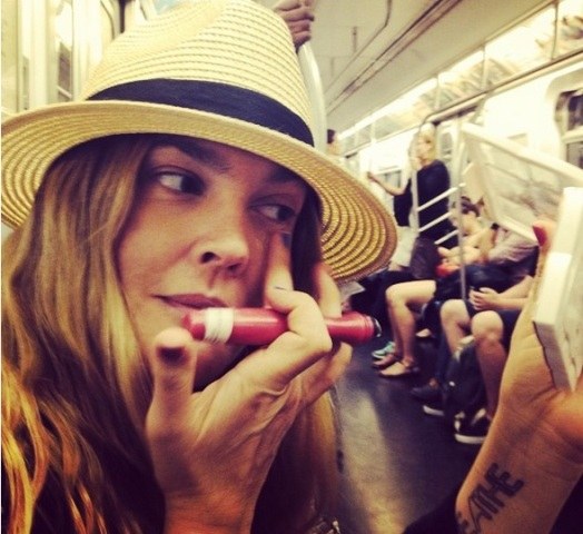 Drew Barrymore anda de metrô e retoca maquiagem